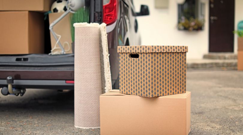 boxes and a rolled up rug next to a van